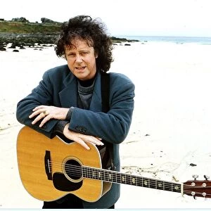 Donovan Pop Star of the 60s pictured at a beach with his guitar hanging around his neck