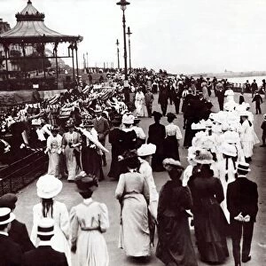 Edwardian Ladies and Gentleman walk up and down the promenade of an unnamed English South