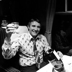 Football manager Malcolm Allison drinking champagne n the train