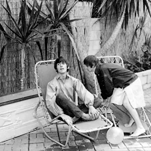 George Harrison and Ringo Starr relax by their swimming pool in Bel Air California