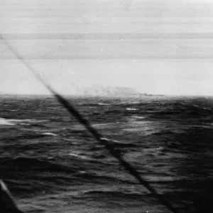 The German battleship Bismarck burns on the horizon approximately 350 miles west of