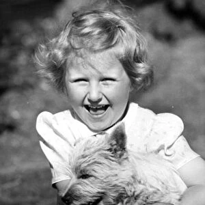 Happy young girl holding onto her pet dog Circa 1945 P044448