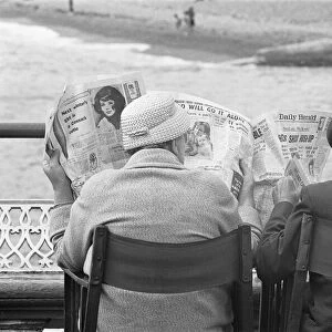 Holiday scenes at Brighton. Elderly couple reading the Daily Herald on Brighton
