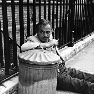 James Mason Actor leaning on a dustbin and fence