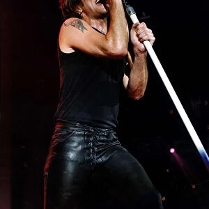 Jon Bon Jovi Pop Singer for Bon Jovi group on stage singing into microphone