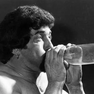 Male Stripper mel blowing into a milk bottle. June 1977 P018599