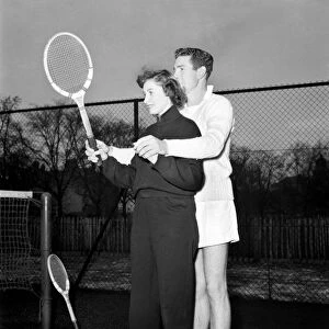 Man giving woman instruction on how to hold the tennis racket before a game
