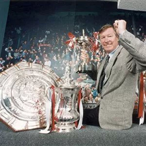 Manchester United manager Alex Ferguson posing with the trophies won in the 1993 - 1994