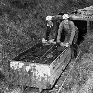 Two men pushing a cart full of coal in a mine. July 1978 P018160