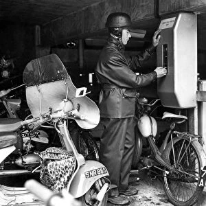 A motor cyclist puts his sixpence in the ticket machine in the new motor cycle "