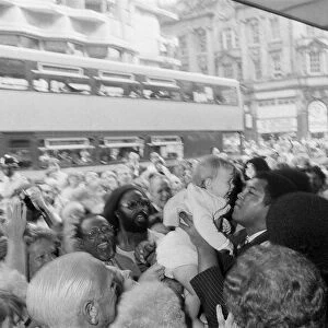 Muhammad Ali holds up a baby on his visit to Birmingham. 9th August 1983