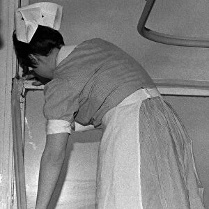A nurse tapes up a draughty window in an Infirmary ward. 10th April 1970