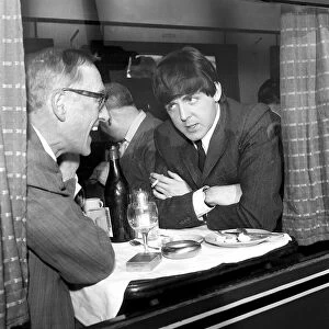 Paul McCartney of The Beatles and actor Wilfred Bramble chat at dining table