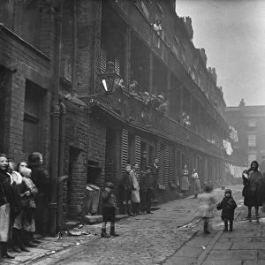People standing between two terraces in a slum housing area of Liverpool. 2nd March, 1933