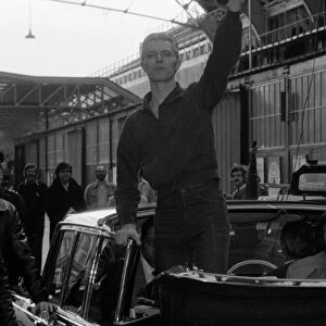 Pop singer David Bowie waves to fans as he arrives at Victoria Station May 1976