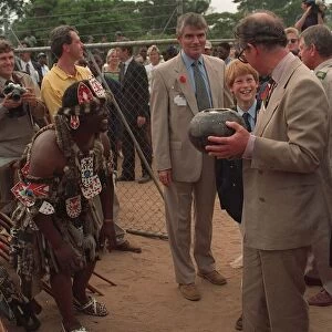 Prince Charles samples the native drink whilst his son Prince Harry watches on their
