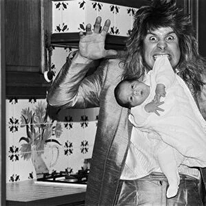 Rock star Ozzy Osbourne dangles two week old baby Jack from his teeth at his home