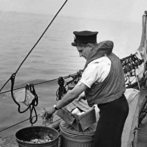 Nothing is wasted at Sea. Picture shows seaman placing waste in salvage tins so familiar