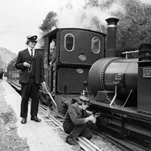 A woker applying some oil to one of the steam trains on the Talyllyn railway line which