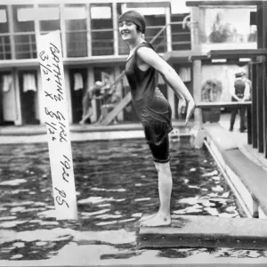 Woman in a 1920s style swimming costume about to dive in to a swimming pool