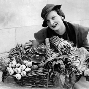 A woman with a selection of in season garden produce. 20th May 1934
