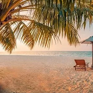 Beautiful tropical sunset scenery, two sun beds loungers umbrella palm tree. White sand, sea view with horizon, colorful twilight sky, beach resort