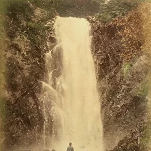 View of the Hodo Cascade at Nikko, Japan. In the foreground, a man seen from the back is observing the cascade