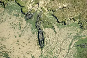 Prints of The wrecks of three barges in Shepherds Creek, Chetney Marshes, Kent, 2024 Aerial Views of England - Landscapes, Cities and Heritage from Above: Barge Wrecks Print: Aerial View of Three Sunken Barges in Shepherds Creek