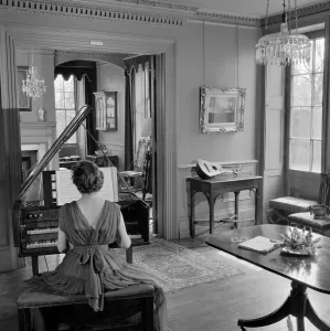 Prints of FENTON HOUSE, Hampstead, London. Interior view showing a woman in evening dress playing the harpsichord. Photographed by John Gay. Date range: 1960-1965 House And Home Prints: Print of a Woman Playing Harpsichord in Evening Dress