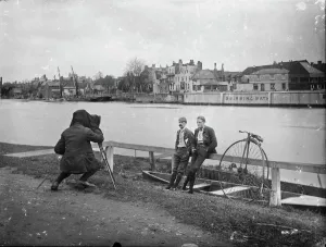 Print of Two Men with Penny Farthing Bicycle on the River Thames Bank
