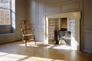 Prints of GREAT YARMOUTH ROW HOUSES, Norfolk. Row 111. Interior view with sun shining through a window onto a chair and fireplace House And Home Prints: Great Yarmouth Row House Print: Interior Scene