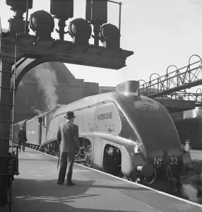 Prints of MALLARD. View of the LNER Class A4 train during its time on the Flying Scotsman express passenger service between London and Edinburgh. A man in a trilby hat looks at the engine Iconic Photographers of England - Historic Image Collections: Print of Mallard steam train in service on the Flying Scotsman express