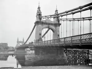 Prints of HAMMERSMITH BRIDGE, Barnes, Greater London. This decorative suspension bridge is seen here from the riverbank Iconic Photographers of England - Historic Image Collections: Hammersmith Bridge Print, 1895