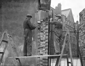 Prints of Millbank Estate, Erasmus Street, Millbank, City of Westminster, Greater London. Two workmen repairing bomb damage to London Council Council (LCC) flats on the Millbank Estate Engineering And Construction Prints: Print of workmen repairing bomb damage to Millbank Estate flats