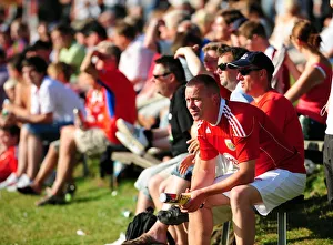 Fans from both teams sit in the sun to watch the game Fans from both teams sit in the sun to watch the game