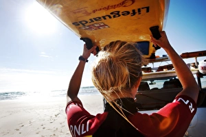 Female lifeguard lifting rescue boards down from a patrol vehicle Female lifeguard lifting rescue boards down from a patrol vehicle
