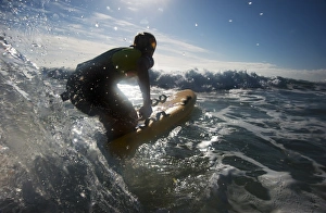 Female lifeguard paddling out through surf on a rescue board at Constantine Bay, Cornwall Female lifeguard paddling out through surf on a rescue board at Constantine Bay, Cornwall