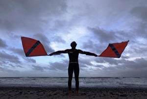 Lifeguard on Cromer beach waving two red flags. Silhouette Lifeguard on Cromer beach waving two red flags. Silhouette