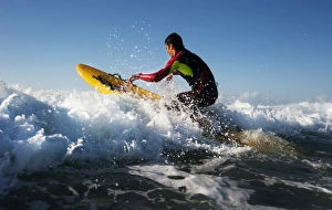 Lifeguard paddling out through surf on a rescue board at Constantine Bay, Cornwall Lifeguard paddling out through surf on a rescue board at Constantine Bay, Cornwall