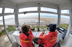 Two lifeguards monitoring the sea at a beach in Jersey from lifeguard hut Two lifeguards monitoring the sea at a beach in Jersey from lifeguard hut