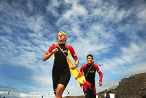 Two lifeguards running along the beach towards the camera, taken from below looking up Two lifeguards running along the beach towards the camera, taken from below looking up