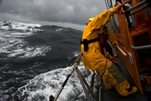 Lizard Tyne class lifeboat David Robinson 47-030 in rough weather. Crew members can be seen holding onto the side of Lizard Tyne class lifeboat David Robinson 47-030 in rough weather. Crew members can be seen holding onto the side of