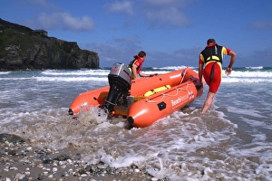 Two RNLI lifeguards launching an Arancia inshore rescue boat Two RNLI lifeguards launching an Arancia inshore rescue boat