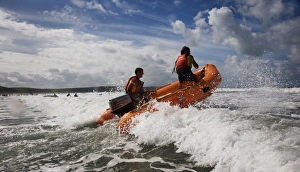 Two RNLI lifeguards in the surf at Woolacombe beach, Devon on an arancia inshore rescue Two RNLI lifeguards in the surf at Woolacombe beach, Devon on an arancia inshore rescue
