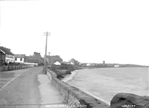 Prints of Ballyhalbert, Co. Down - a view looking along the shore wall of the town with sea on the right and buildings to the left, curving in the distance County Down Prints: Ballyhalbert, Co. Down Print - Early 1900s