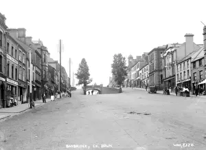 Prints of Banbridge, Co. Down - a view looking up the Main street and Bridge with shop fronts and people and motor cars. (Location: Northern Ireland; County Down; Banbridge). Date: circa early 1900s Down Prints: Early 20th Century Print of Banbridge, Co. Down