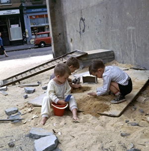 Three boys playing with sand in a Balham street, SW London Three boys playing with sand in a Balham street, SW London