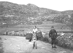 Prints of In Co. Donegal - a view of a girl sitting on a donkey and creel and a boy standing beside her in the mountains. (Location: Republic of Ireland; County Donegal; Rosguil). Date: circa early 1900s Related Prints: Early 20th Century Irish Print: Donegal Mountain Scene