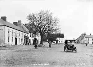 Prints of Coagh, Co. Tyrone - a street scene looking up from above. On the left is the Royal Hotel and the motor car and the water wheel to the right.. (Location: Northern Ireland: County Tyrone: Coagh) Tyrone Prints: Coagh Street Scene Print, Northern Ireland, Early 1900s