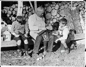 Prints of Two little boys help an old clockmaker, perhaps their grandfather, to make a cuckoo clock in the Black Forest, Germany Cuckoo Prints: Black Forest Cuckoo Clock Maker Print